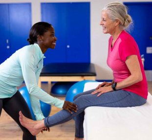 caregiver helping senior woman stretch her legs