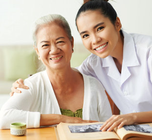 smiling caregiver and senior woman reading a book