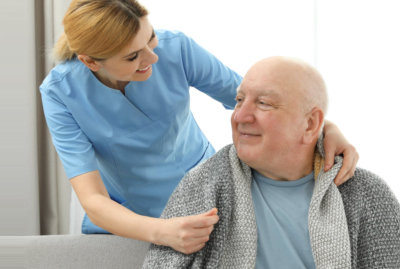 caregiver giving blanket to a senior man