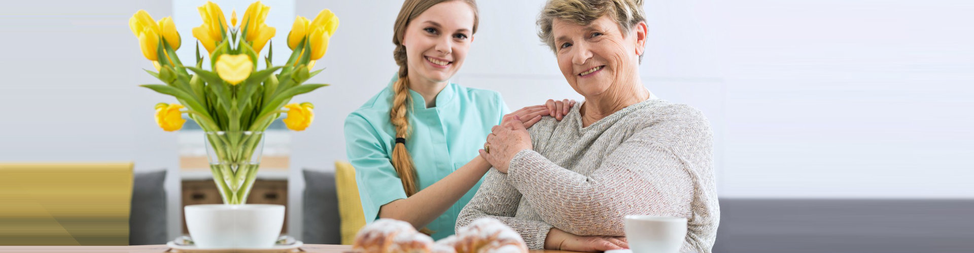 happy caregiver and senior woman in a dining room